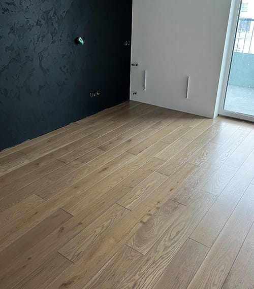 Close-up of installed engineered hardwood flooring in a bright, modern living room